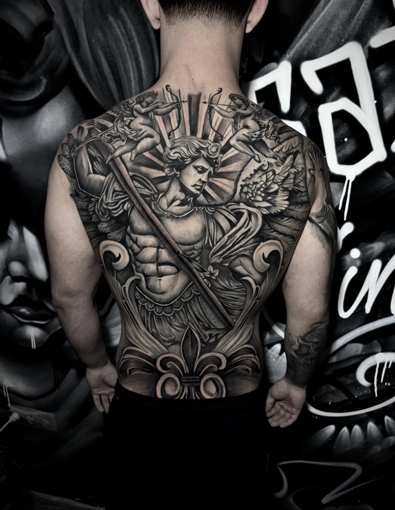 Espalda completa tatuada en realismo black and grey con figuras clásicas y ornamentos